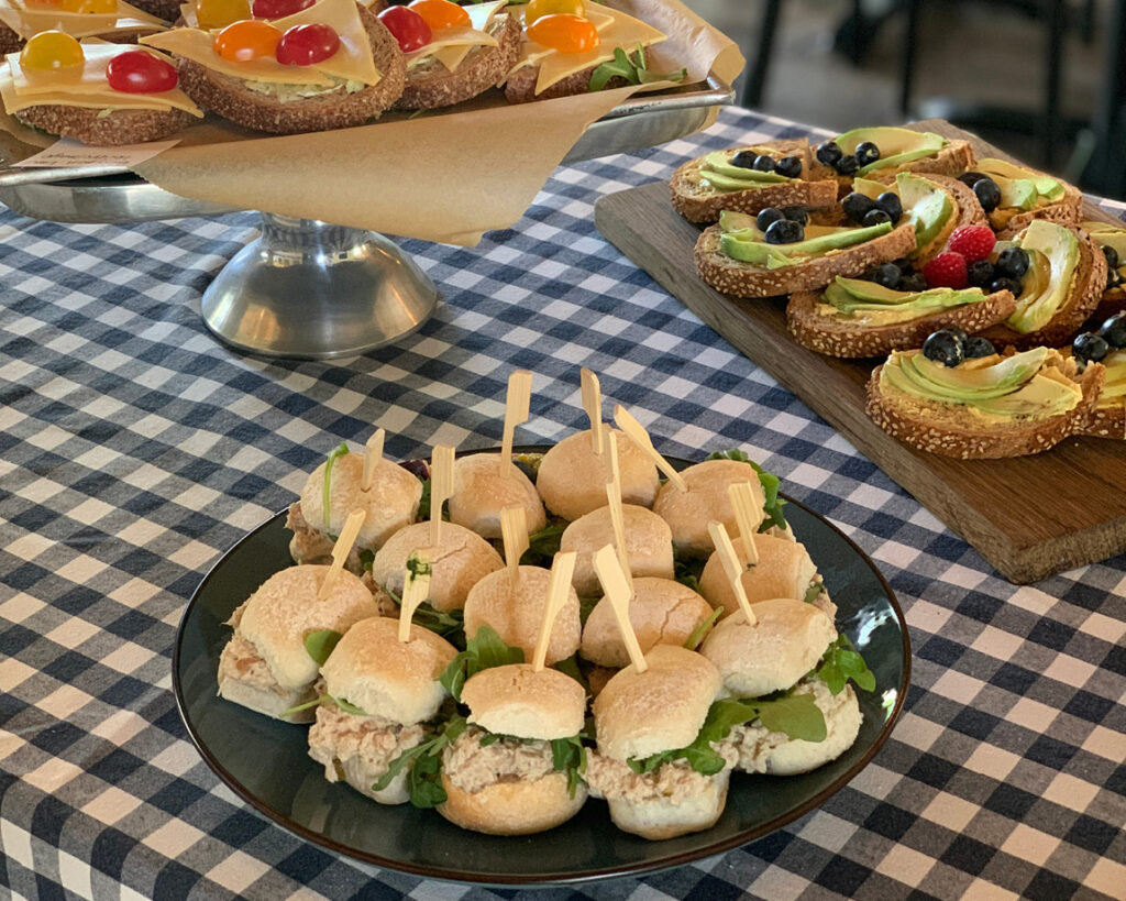 Ambachtelijke belegde broodjes gepresenteerd op een houten plank voor zakelijke catering.